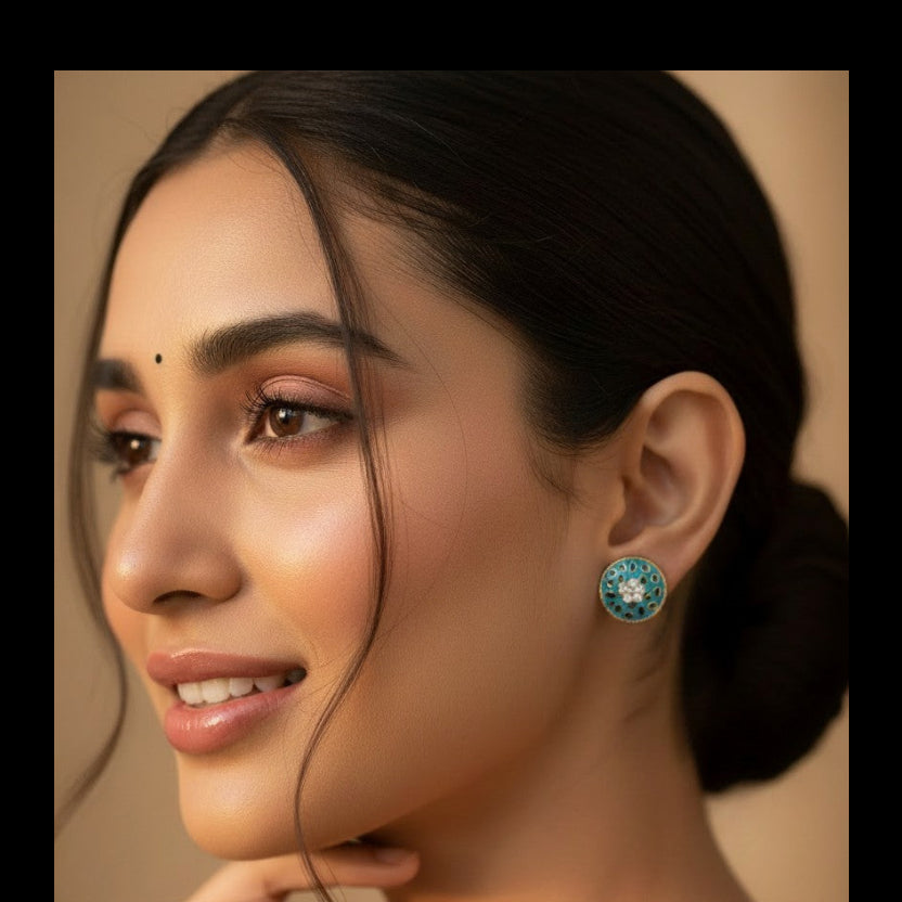 A close-up portrait of a woman wearing a round turquoise and white beaded earring, with her hand near her chin against a warm beige background.