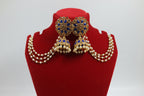 Gold-toned traditional Indian jhumka earrings with deep blue stone inlay and a matching pearl-beaded choker necklace, displayed on a white jewelry bust.