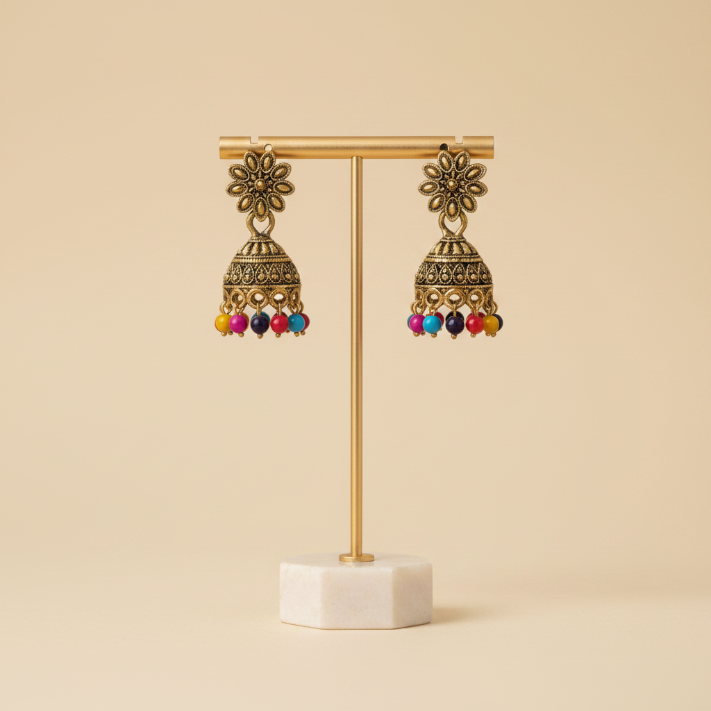 A close-up of a person's ear wearing an ornate gold-toned jhumka earring with multiple dangling colorful beads.