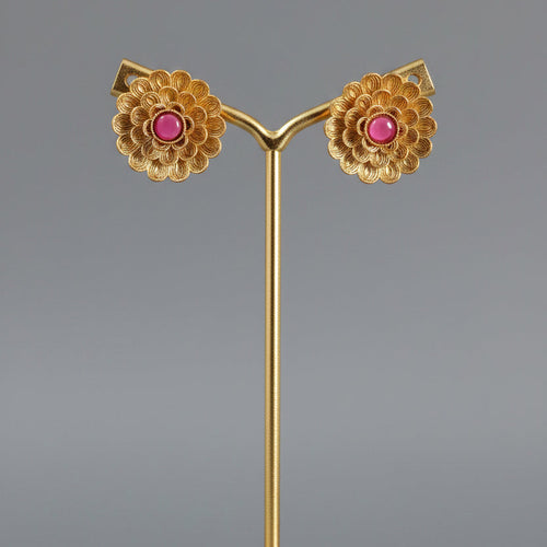A pair of gold-toned floral mandala stud earrings with ruby-red stone centers, displayed on a plain background.