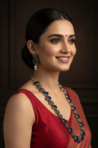 A silver-toned jewelry set featuring a necklace, matching earrings, and a bracelet, each adorned with alternating dark blue oval stones and textured silver oval links, displayed on a white marble surface.