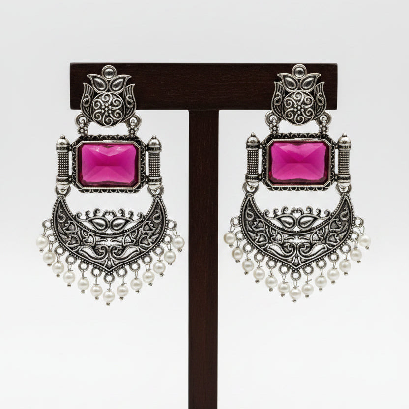 A pair of silver-toned traditional Indian chandelier earrings with rectangular pink gemstones and white pearl bead fringe, displayed on a white card labeled 'Fashion Jewellery'.