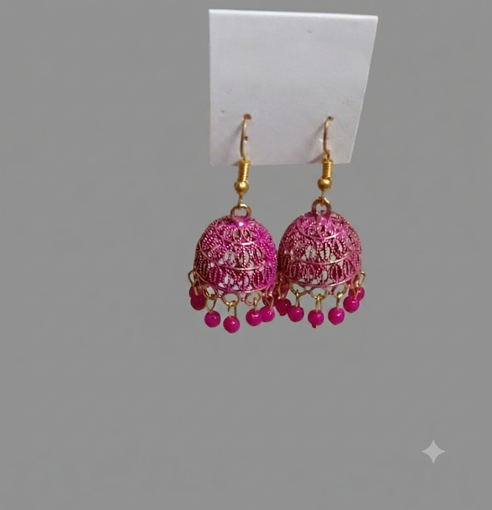 A pair of traditional Indian jhumka earrings with pink beaded fringe and gold-tone hooks, displayed on a white card against a solid gray background.