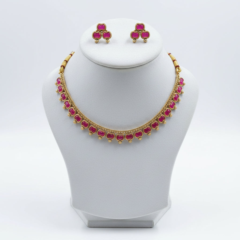 Gold-tone jewelry set featuring a necklace and matching earrings with pink heart-shaped stones, displayed on a black velvet jewelry bust.