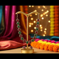 Gold-plated necklace and matching stud earrings set with alternating red and green round stones, displayed on a clear plastic card over a dark blue patterned fabric background.