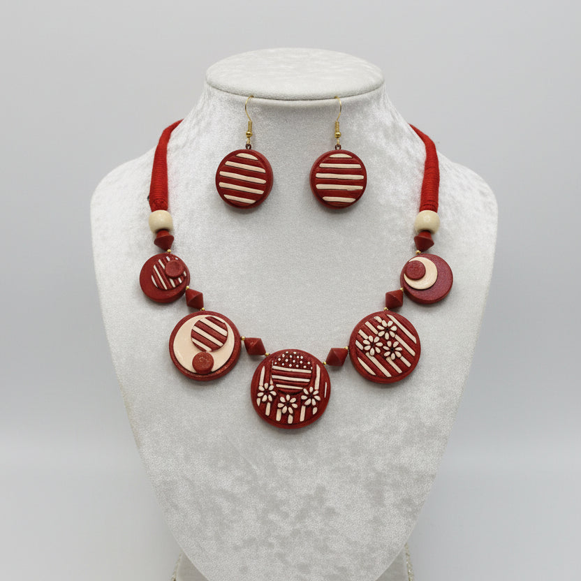 A red and cream beaded jewelry set featuring a beaded necklace and matching earrings with circular designs, laid out on a white faux fur background.