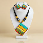 A handcrafted Terracotta Multicolour Statement Necklace Set in blue, yellow, and green tones, displayed with matching earrings.