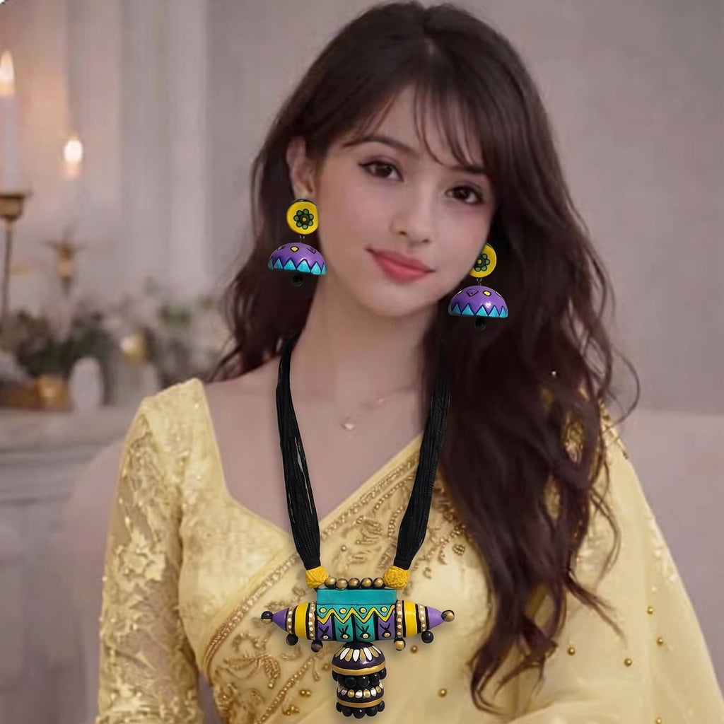 A woman wearing a light yellow embroidered saree with a matching blouse, styled with a colorful beaded necklace, matching earrings, and bangles, seated on a light-colored sofa.