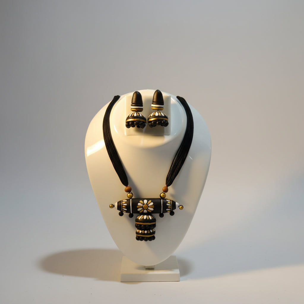 A black and gold clay jewelry set displayed on a white mannequin bust, featuring a necklace with a decorative pendant and matching earrings.