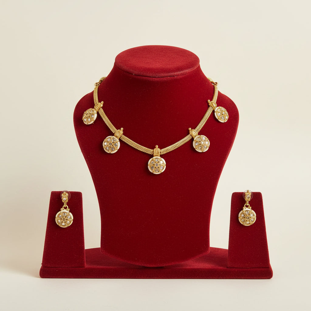 Gold jewelry set featuring a necklace and matching earrings displayed on black velvet stands. The necklace has a textured gold chain with five round, heavily embellished gold pendants, while the matching earrings have similar round pendant designs hanging from smaller gold hooks.